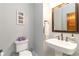 Small bathroom with a pedestal sink, toilet, mirror and decorative artwork at 1268 Harris Road Rd, Lawrenceville, GA 30043