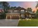 Charming two-story home at dusk with a manicured lawn, a two-car garage, and beautiful landscaping at 1268 Harris Road Rd, Lawrenceville, GA 30043