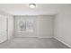 Neutral bedroom showcasing a window with blinds, a single light fixture, light gray walls and carpeted flooring at 7099 Skippingstone Way, Douglasville, GA 30134
