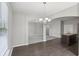 Open dining room with modern chandelier, wood floors, and view of the kitchen island at 7099 Skippingstone Way, Douglasville, GA 30134