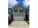 Charming townhome featuring a two-car garage and neat landscaping under a partly cloudy sky at 776 Woodstock Grove Dr, Woodstock, GA 30188