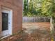 Backyard view featuring a brick wall, mature trees, and leaves scattered across the driveway at 1723 Fort Valley Sw Dr, Atlanta, GA 30311