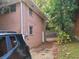 Exterior view of the brick home and driveway leading to a backyard featuring a retaining wall and lush foliage at 1723 Fort Valley Sw Dr, Atlanta, GA 30311