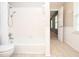 Bright bathroom with white tiled tub and shower, wainscoting, and view to hall at 4714 Marc Sw Ct, Lilburn, GA 30047