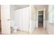 Bathroom with white tile floor, white tub with shower curtain, and a hallway view at 4714 Marc Sw Ct, Lilburn, GA 30047