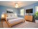 Staged bedroom featuring a light wood bed frame, blue walls, and two windows at 4714 Marc Sw Ct, Lilburn, GA 30047