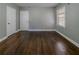 Spacious bedroom with dark wood floors, light-grey walls, a window, and two white doors at 1555 Rupert Rd, Decatur, GA 30032