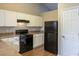 Bright kitchen with white cabinets, black appliances, and wood-look flooring at 2105 Sandtree Sw Ct, Atlanta, GA 30331