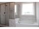 Bright bathroom featuring tiled walls, a glass enclosed shower, and a soaking tub under a window at 4933 Greenard Watson Ln, Buford, GA 30518