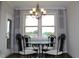 Elegant dining area with glass-top table and ornate chandelier, bathed in natural light from the large window at 4933 Greenard Watson Ln, Buford, GA 30518