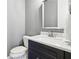 Powder room featuring marble countertop, dark cabinets, mirror, toilet, and towel bar at 2362 Saint Davids Nw Sq, Kennesaw, GA 30152