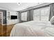 Primary bedroom with white bedding, plantation shutters, hardwood flooring, TV, and built in cabinet at 2362 Saint Davids Nw Sq, Kennesaw, GA 30152