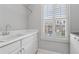Bright laundry room featuring a utility sink, white cabinetry, and window with white shutters at 2362 Saint Davids Nw Sq, Kennesaw, GA 30152