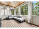 View of covered porch with gray sectional sofa, ceiling fan, wood panel ceiling and green scenery at 2362 Saint Davids Nw Sq, Kennesaw, GA 30152