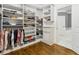 Custom designed walk-in closet with shelves and hanging rods. Hardwood floors extend into a bathroom suite at 2362 Saint Davids Nw Sq, Kennesaw, GA 30152