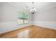 Bright, empty dining room with hardwood floors, elegant chandelier, and a large window at 607 Little Shoals Ct, Canton, GA 30115