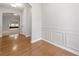 Dining room featuring hardwood floors, white wainscoting, and an archway leading to a carpeted living space at 607 Little Shoals Ct, Canton, GA 30115