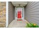Close-up of the bright red front door with sidelights, complemented by stone and gray siding at 607 Little Shoals Ct, Canton, GA 30115