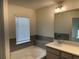 Bathroom with soaking tub, gray tiling, window with blinds, and single sink vanity at 7695 Baron Rd, Fairburn, GA 30213