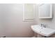 Bathroom features a classic pedestal sink with a mirror and window for light at 10149 Puckett Sw St, Covington, GA 30014