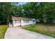 Street view of light gray brick home featuring a concrete driveway and lush surrounding trees at 10149 Puckett Sw St, Covington, GA 30014