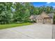 Charming exterior with stone accents, a large driveway, and a manicured lawn surrounded by lush trees at 561 Holland Rd, Dallas, GA 30157