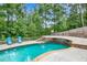 Gorgeous backyard pool area featuring a stone retaining wall, inviting lounge chairs, and lush greenery at 561 Holland Rd, Dallas, GA 30157