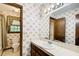Bathroom features floral wallpaper, tiled floors, and single sink vanity with dark wood cabinets at 2612 Spring St, Dacula, GA 30019