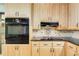 A close up view of the kitchen features maple cabinets, black appliances and decorative backsplash at 2612 Spring St, Dacula, GA 30019