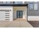 Modern home's entry featuring a three-car garage with a walkway to a glass double door entrance at 52 Deer Canyon Dr, Auburn, GA 30011
