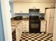 Efficient kitchen with white cabinets, a black stove and oven, and a black-and-white checkered floor at 852 Glynn Oaks Dr, Clarkston, GA 30021