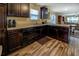 Well-lit kitchen with wood floors, stainless steel sink and dark wood cabinets and counters at 110 Baltusrol Way, Covington, GA 30014