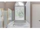 Bright bathroom featuring a soaking tub with a large window and a glass-enclosed shower at 1721 Crowes Lake Ct, Lawrenceville, GA 30043