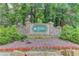 Entrance to the The Lakes community featuring a stone sign surrounded by landscaping and flowers at 1721 Crowes Lake Ct, Lawrenceville, GA 30043