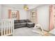 Bright bedroom with plush carpet, gray sectional, white crib, and pink drapes at 2955 Rhodenhaven Nw Dr, Atlanta, GA 30327