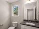 Cozy powder room with granite countertop, toilet, and a framed mirror above the sink at 325 Nutwood Trce, Locust Grove, GA 30248