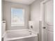 Bathroom featuring a soaking tub with a window, neutral walls, and white door at 325 Nutwood Trce, Locust Grove, GA 30248