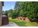 The large backyard features a manicured lawn, mature trees, and a charming stone pathway at 8920 Ellesmere Dr, Cumming, GA 30041