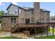 Brick home featuring a wooden deck overlooking the manicured backyard and a stone staircase at 8920 Ellesmere Dr, Cumming, GA 30041