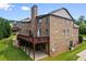 Brick home featuring a wooden deck overlooking the manicured backyard and patio at 8920 Ellesmere Dr, Cumming, GA 30041