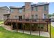 Brick home featuring a wooden deck overlooking the manicured backyard and patio below at 8920 Ellesmere Dr, Cumming, GA 30041