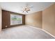 A spacious carpeted bedroom with brown accent wall and large window at 8920 Ellesmere Dr, Cumming, GA 30041