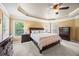 Large bedroom with tray ceiling, fan, and carpet at 8920 Ellesmere Dr, Cumming, GA 30041