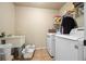 Well-lit laundry room featuring a utility sink and modern washer and dryer units with shelving above at 8920 Ellesmere Dr, Cumming, GA 30041