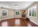 Cozy living room with a stone fireplace, wood floors, and lots of natural light from multiple windows at 8920 Ellesmere Dr, Cumming, GA 30041