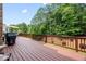 Wooden deck is furnished with seating, a grill, and overlooks green backyard and mature trees at 8920 Ellesmere Dr, Cumming, GA 30041