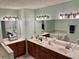 Bright bathroom with dual vanities, large mirrors, and a soaking tub in the background at 403 Hickory Walk, Woodstock, GA 30188