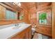 Bathroom with wood paneling, a sink with a mirror, a toilet, and a window at 521 East Valley Ne Rd, Rydal, GA 30171