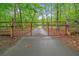 Gated driveway with a red metal gate amidst lush green trees and vegetation at 521 East Valley Ne Rd, Rydal, GA 30171