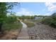 Community stream with a rock bed and grassy banks, connected by a wooden bridge under a sunny sky at 992 Harvest Park Ln, Suwanee, GA 30024